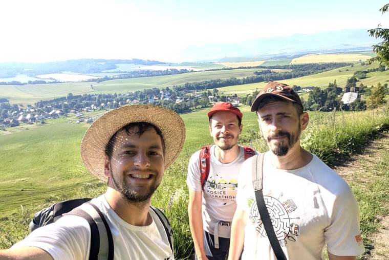 Martin with two teammates on a hike above a village